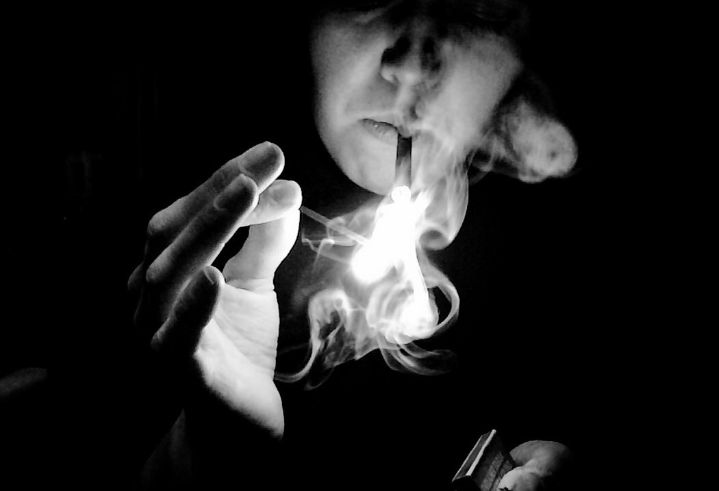 Person lighting a cigarette, dramatic light and smoke