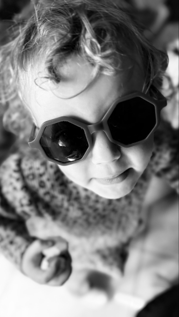 Child in hexagonal sunglasses, looking up